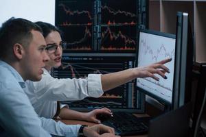 Looks like we must achieve that line. Team of stockbrokers are having a conversation in a office with multiple display screens photo