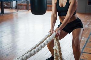 Holds white ropes. Blonde sport woman have exercise in the gym. Strong female photo