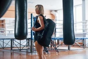 Side view. Adult female with black bag and headphones in the training gym photo