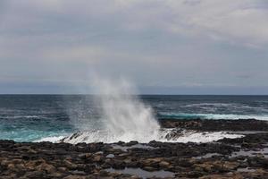 Las olas turbulentas del océano con espuma blanca golpean las piedras costeras. foto