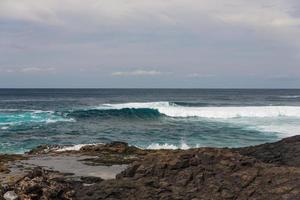 Turbulent ocean waves with white foam beat coastal stones photo