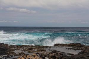 Las olas turbulentas del océano con espuma blanca golpean las piedras costeras. foto