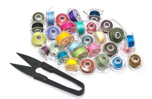 Colorful bobbins with scissor on white background photo