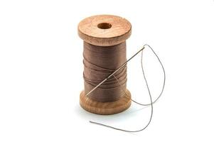Isolated wooden spool of brown thread with a needle photo