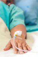 mano del paciente con inyección de goteo de medicina, señora en una cama en un hospital foto