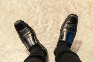 Top view of old black pants and leather shoes of relax sitting businessman on cement floor. Photo is focused at shoes.