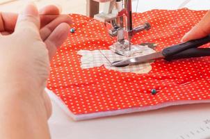 Sewing machine focus at its needle with soft blur of woman hands and scissor photo