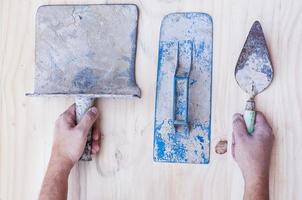 herramientas de mano de construcción antigua con las manos sobre fondo de madera foto
