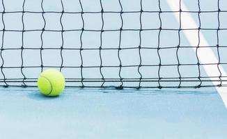 pelota de tenis con fondo de red de pantalla negra en la cancha de tenis azul duro - concepto de competencia de torneo de juego de tenis foto