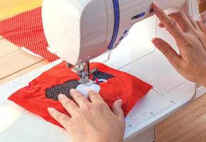 manos de mujer, haciendo su patchwork usando máquina de coser foto