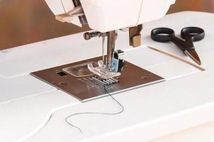 White sewing machine with scissors and thread photo