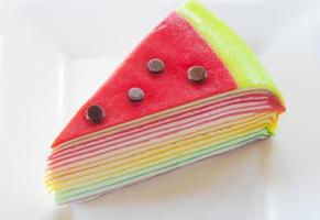 Rainbow crepe cake on a white plate photo