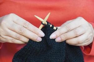 Woman's hands is making black hat knitting photo