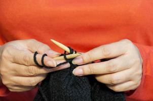 Woman's hands is making black hat knitting photo