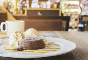 pastel de lava de chocolate en plato blanco con taza de café en la cafetería foto