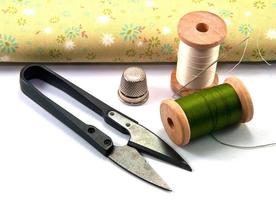 Thimble,needle,spools and scissor with cloth for sewing on white background photo