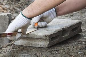 el trabajador de la construcción está trabajando con la medición de bloques de cemento preparándose para el corte. foto