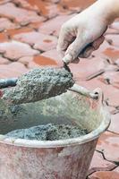 Hand holding trowel mixing mortar in a bucket photo