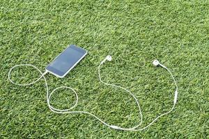 Mobile phone with head phone on green artificial grass photo