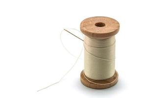 Isolated wooden spool of cream thread with a needle photo