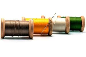 Isolated wooden spools of thread with a needle photo