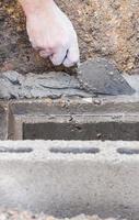 Construction worker is working with cement block on site installation. Manhole cover of housing drainage pipe installation. photo