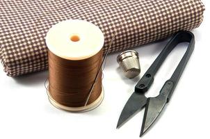 Thimble,needle,spools and scissor with cloth for sewing on white background photo