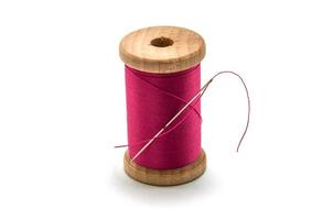 Isolated wooden spool of pink thread with a needle photo