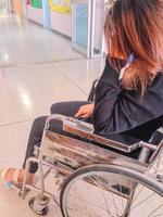 Joven mujer con dolor de cabeza sentada en silla de ruedas en el hospital foto