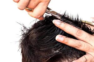 peluquero está cortando el pelo de un niño sobre fondo blanco, concéntrese en la tijera foto