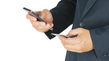 Businessman is using mobile phone and holding card on another hand isolated over white background. Photo includes clipping path around outer edge.