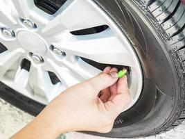 la mano está quitando las tapas de las válvulas de los neumáticos verdes para el servicio de inflado de neumáticos con nitrógeno foto