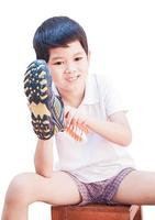 A boy is happily cleaning his shoe isolated on white background photo