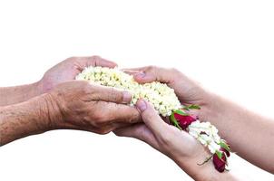 Young hands give jasmine garland to the older as Thai tradition for any special family occasions for paying high respective with love and care. Isolated with clipping path. photo