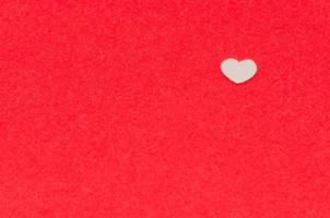 Small white heart shape putting on red background photo