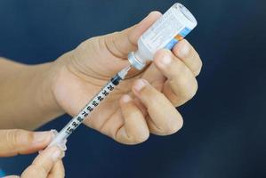 Hands holding Insulin and syringe prepare for injection. Photo is focused at needle area.