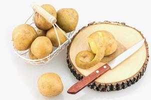 Potatoes in basket with block chopping and knife over white background photo