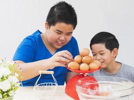 Children are happily weighing raw eggs preparing to make a cake. Photo is focus at the eggs.