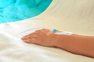 Patient's hand with medicine drip injection, lady on a bed in a hospital photo