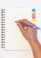 Lady's hand holding pencil ready to write an empty notebook with sticky note memo photo