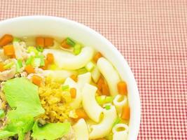 Macaroni soup over red fabric background photo