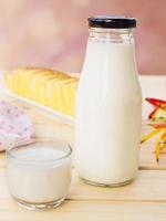 Bottle with glass of milk and butter cake on white wooden table. photo