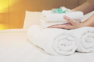 Lady set up white towel set on bed in hotel room photo