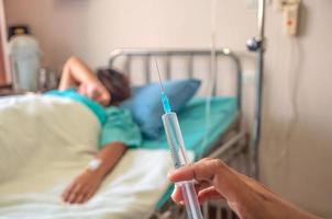 Doctor holding syringe in hand ready for injecting with a patient background in the hospital photo