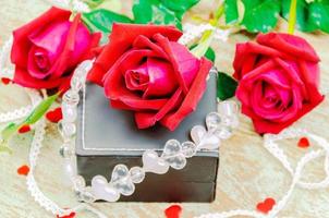 Red roses with heart ornament and gift box decoration. Photo is focused at the middle rose.