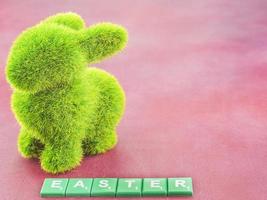 Artificial green grass rabbit and Easter word over pink background photo