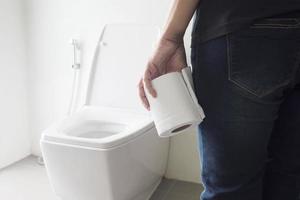 Lady holding tissue near a toilet bowl photo