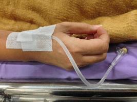 Patient's hand with medicine drip injection, lady on a bed in a hospital photo