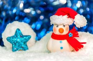 hombre de nieve sobre una franja azul brillante y borrosa, estrella azul y fondo blanco para la decoración navideña de año nuevo foto