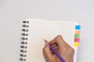 Lady's hand holding pencil ready to write an empty notebook with sticky note memo photo